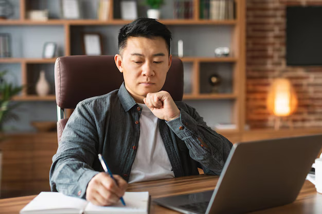 Adult Asian Man Makes Notes Analyzes Data Investment Workplace